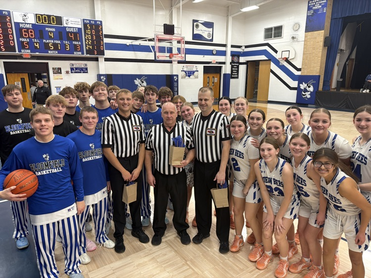 “Bloomfield boys and girls basketball teams gather at center court with game officials after the game, smiling in team uniforms beneath the scoreboard showing a 68–41 final score.”