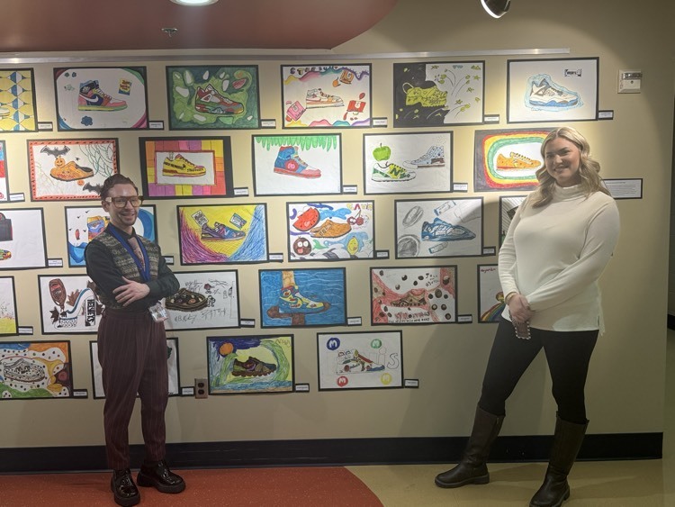 Two teachers standing in front of student art work