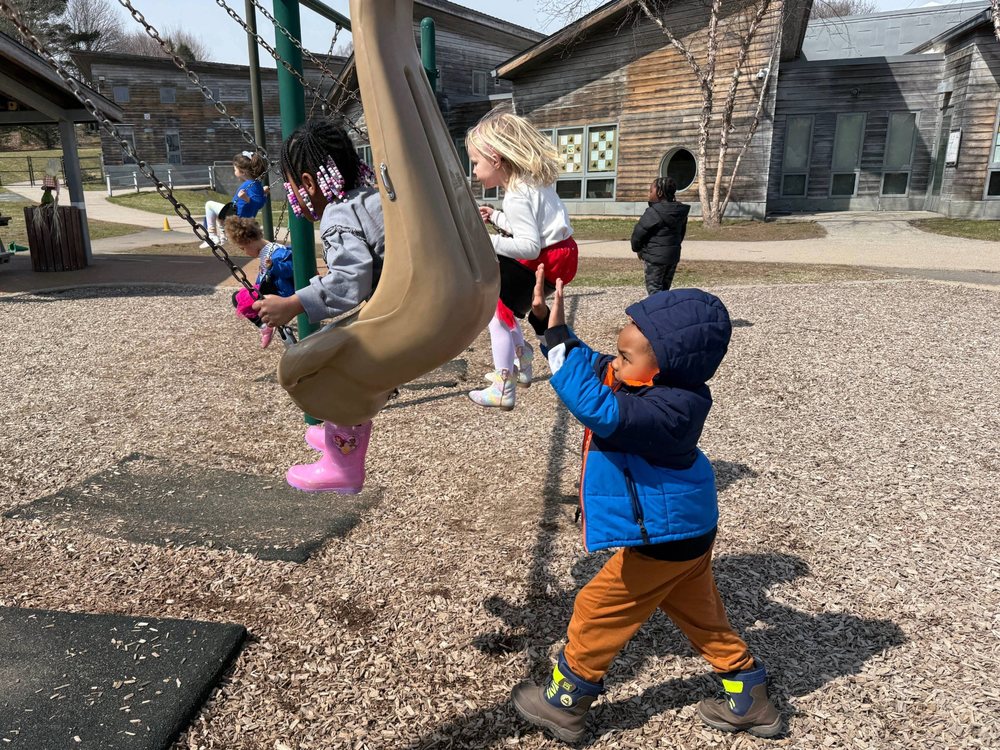 Child pushing another child on a swing swing.