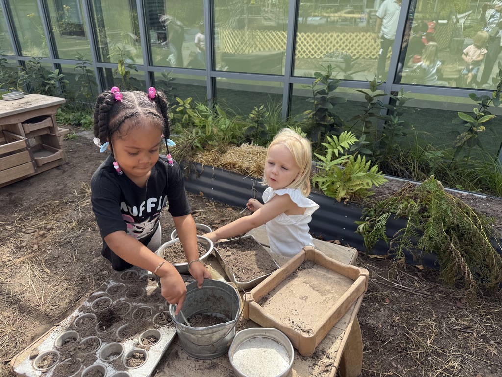 Two girls playing in a mud kitchen.