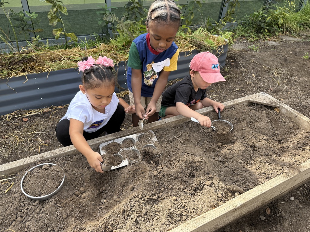 Three young children digging in dirt.