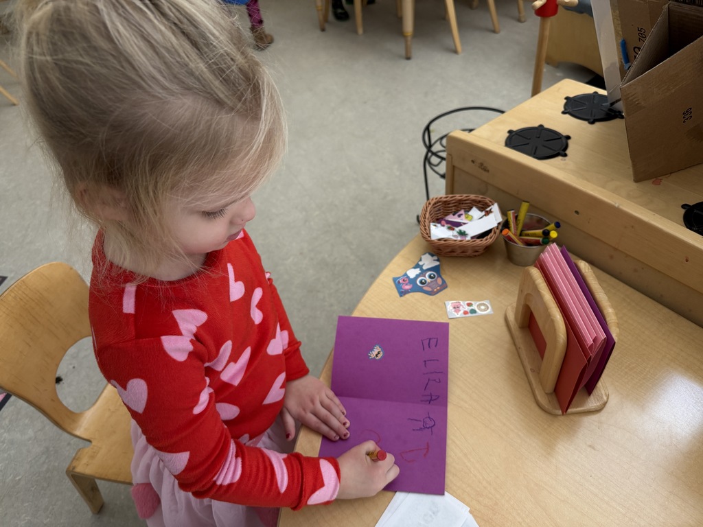 Young girl making a card with stickets and writing.