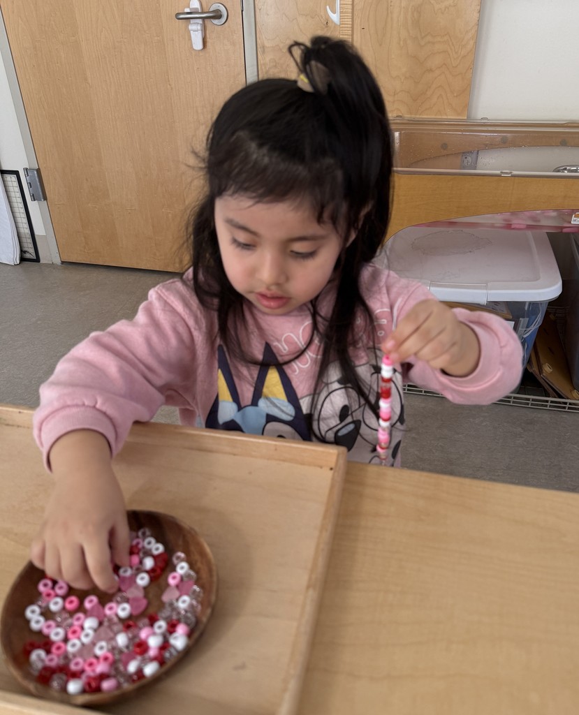 Young girl stsringing beads to make a bracelet.
