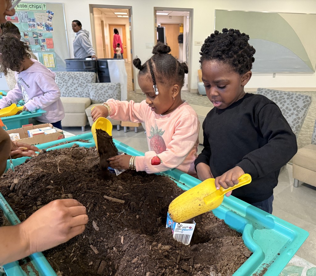 Two young students s coopoing soil into empty milk cartons.