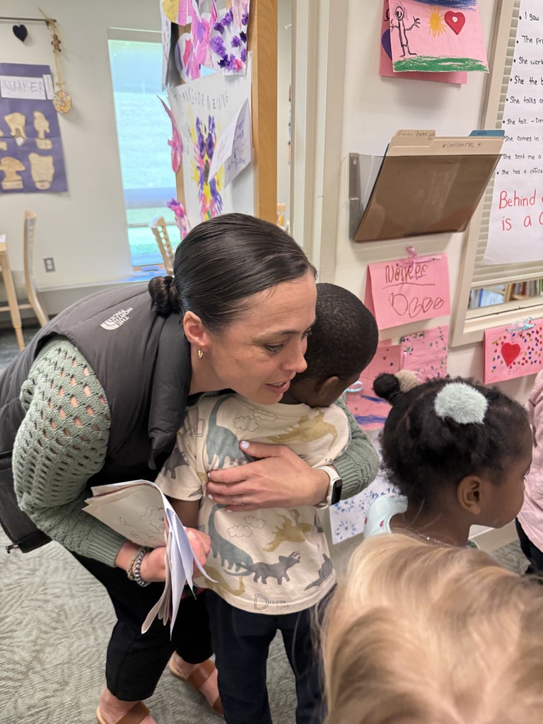 Adult leaning down and hugging child.