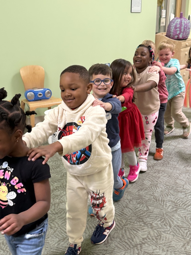 Young children dancing in a train line.