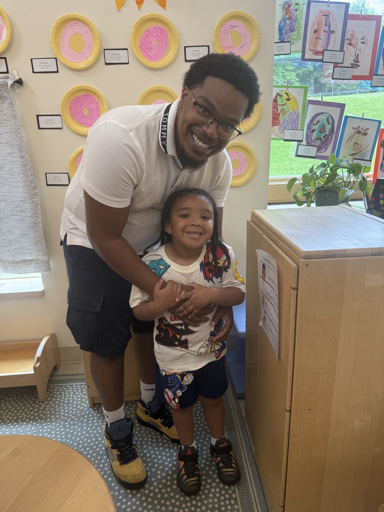 Father and son posing in front of child displayed art work.