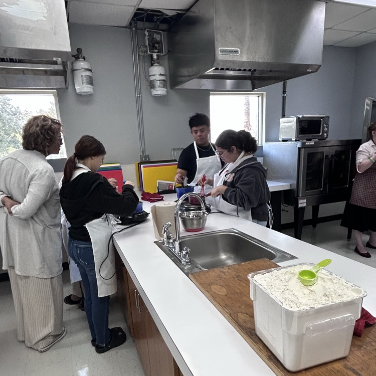 kids cook and teacher looks on 