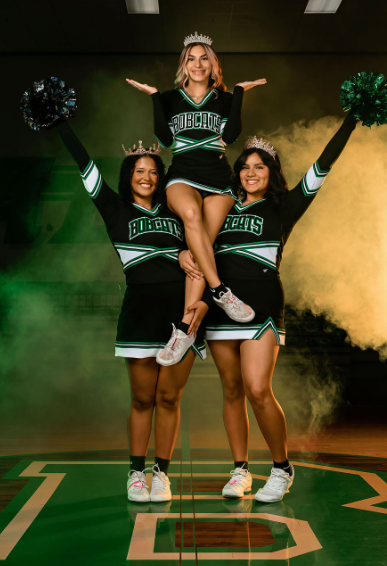 cheerleaders are lifted into stunt with poms and smoke
