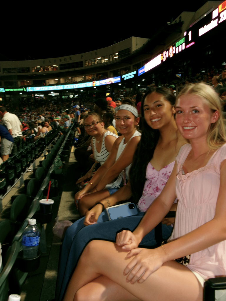 Four girls sitting in seats at a baseball ball park