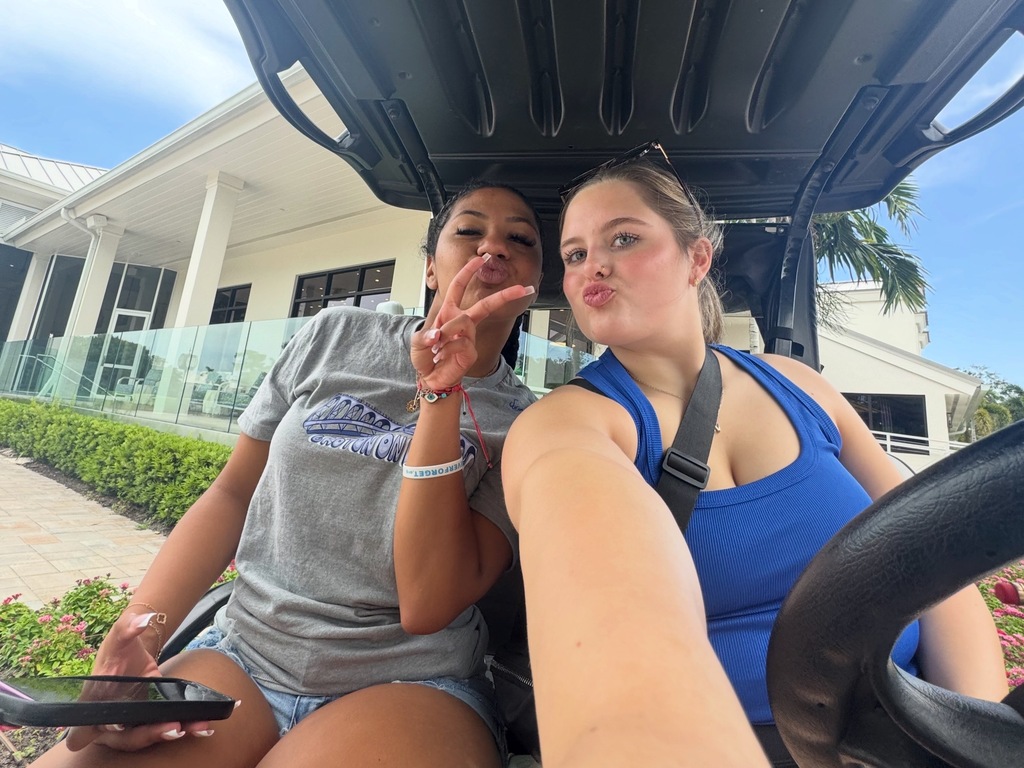 Two girls posing in a golf cart