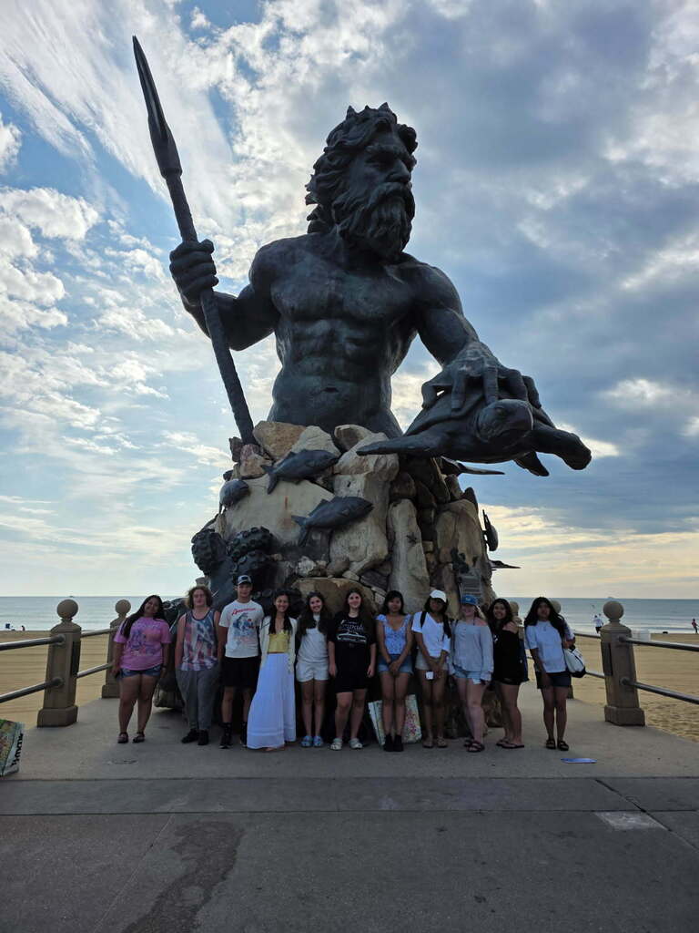 a group of student in front of a statue
