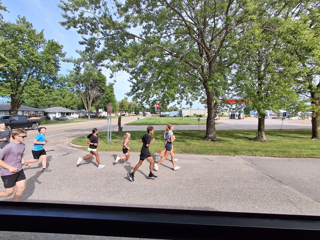 Cross Country team runs the football to Wilson Field