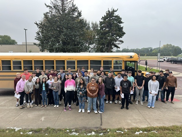 The Junior Class standing in front of a school bus