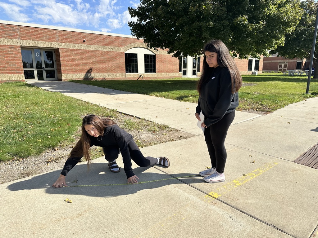 One student standing and another measuring her shadow