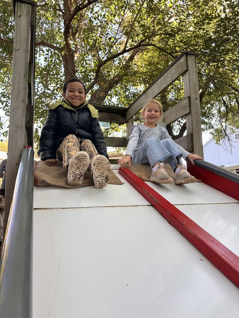 Two students sliding down a slide