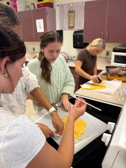 A student cutting out squares to put on the baking sheet