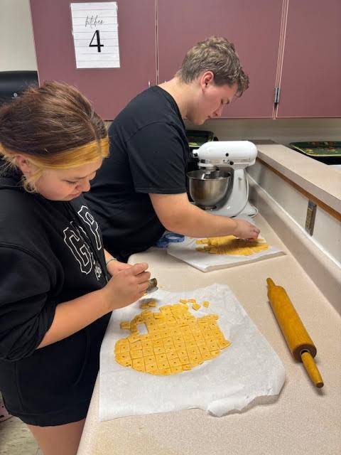 A student cutting out squares to put on the baking sheet