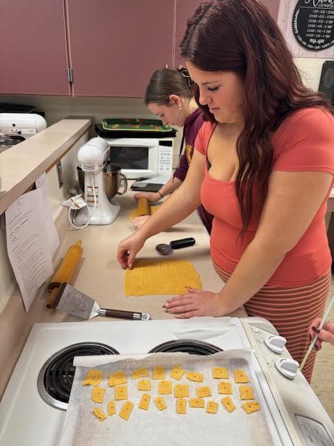 A student cutting out squares to put on the baking sheet