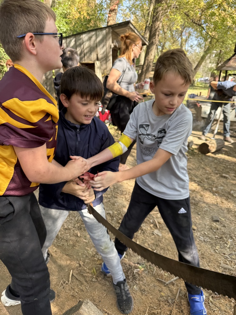 Three boys trying to saw a log