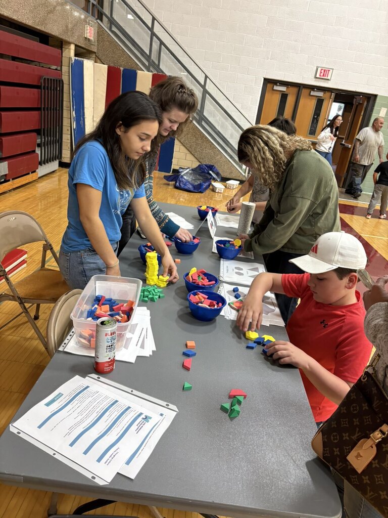 Two high schoolers playing a math game with younger kids