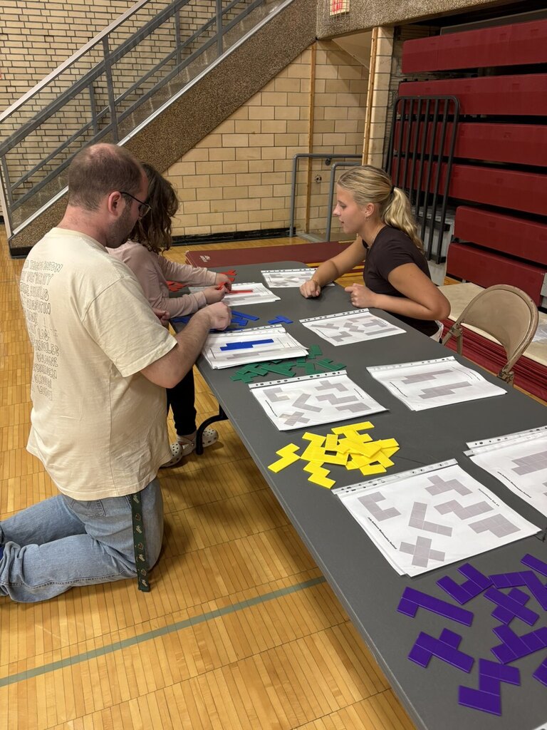 A high schoolers playing a math game with younger kid and her dad.