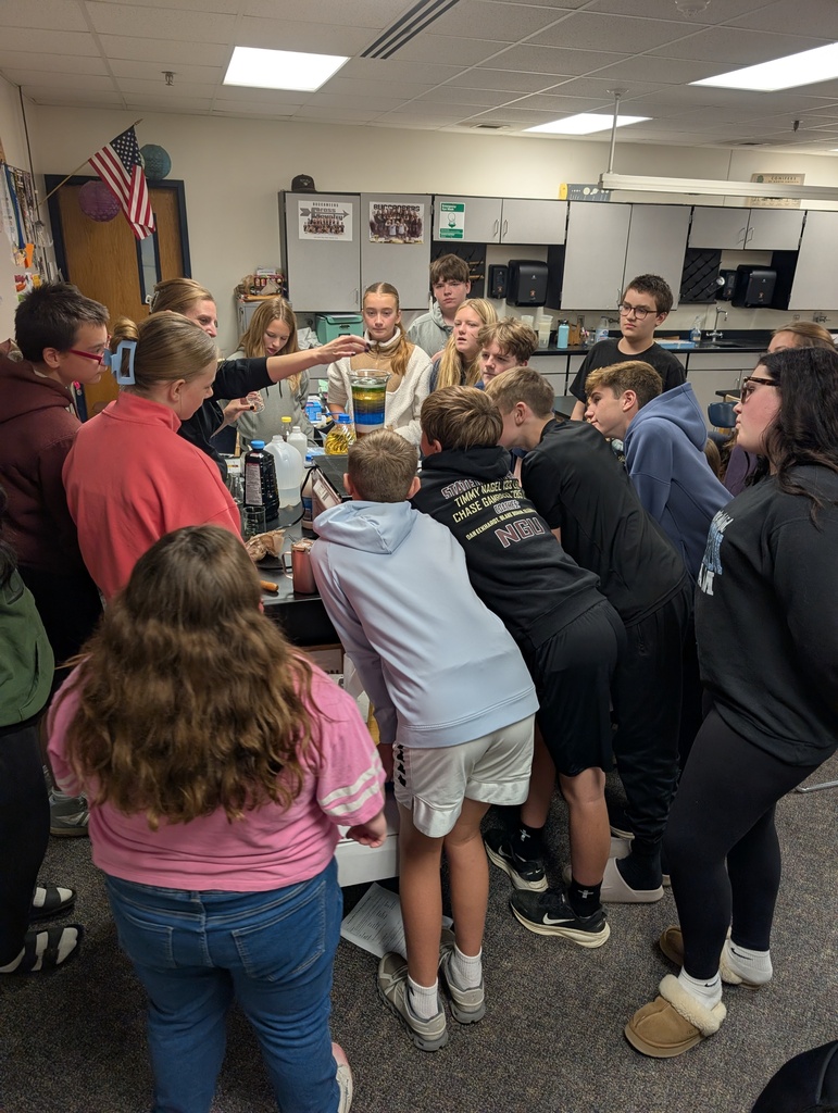 A teacher dropping an object into the container with the different liquids while the students watch.