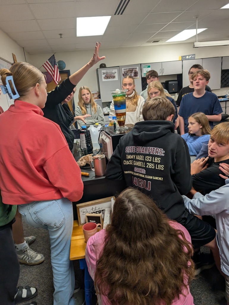 A teacher dropping an object into the container with the different liquids while the students watch.