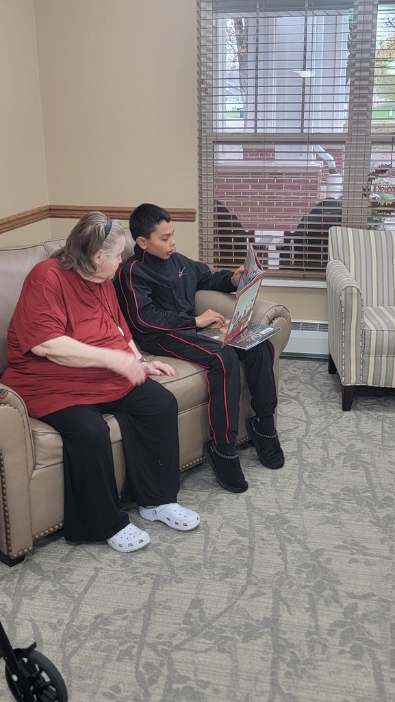 A student reading to a resident at Parker Oaks