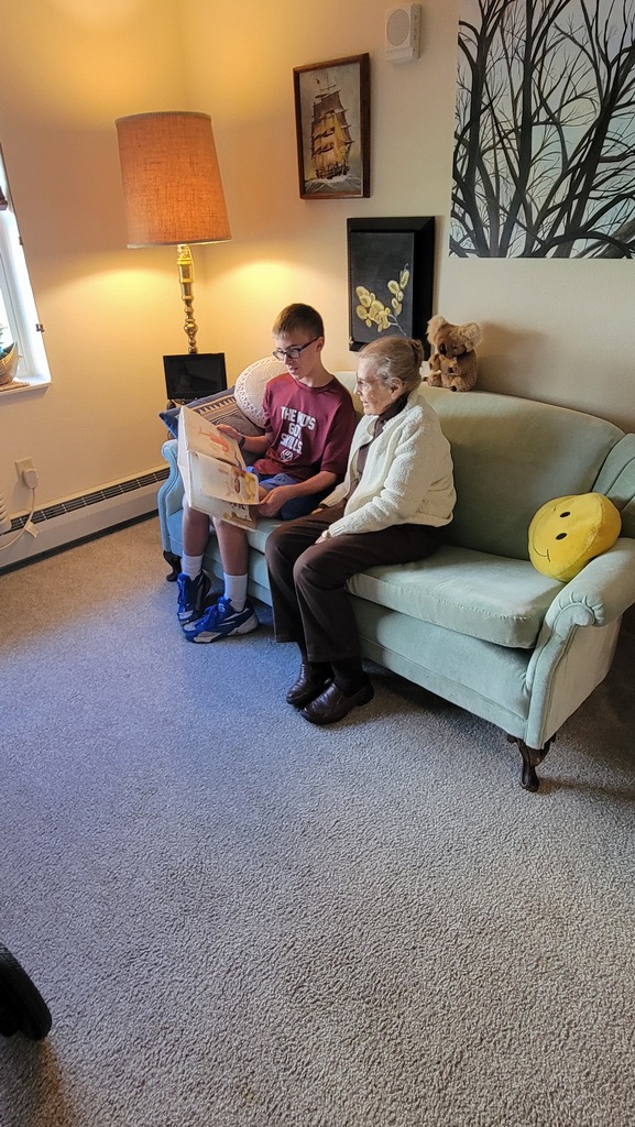 A student reading to a resident at Parker Oaks