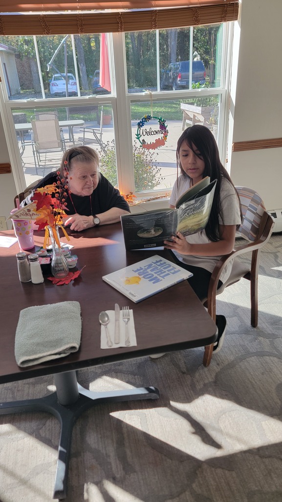 A student reading to a resident at Parker Oaks