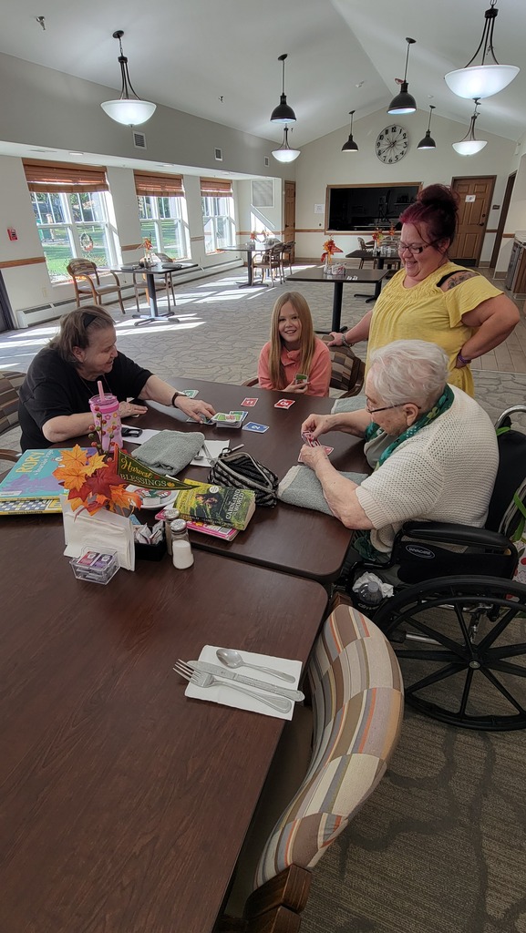 A student playing a card game with 2 residents at Parker Oaks