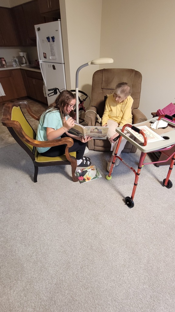 A student reading to a resident at Parker Oaks