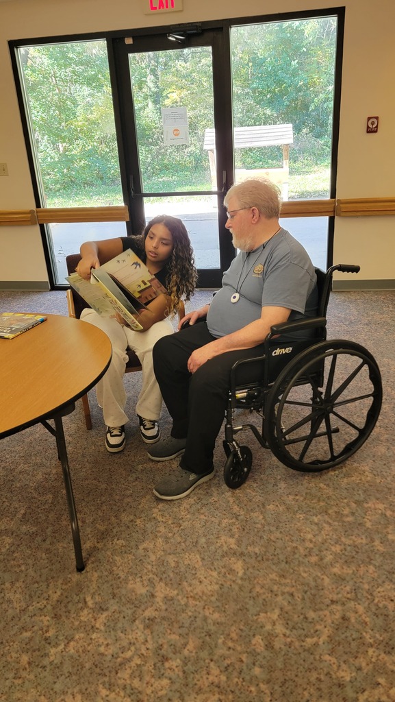 A student reading to a resident at Parker Oaks