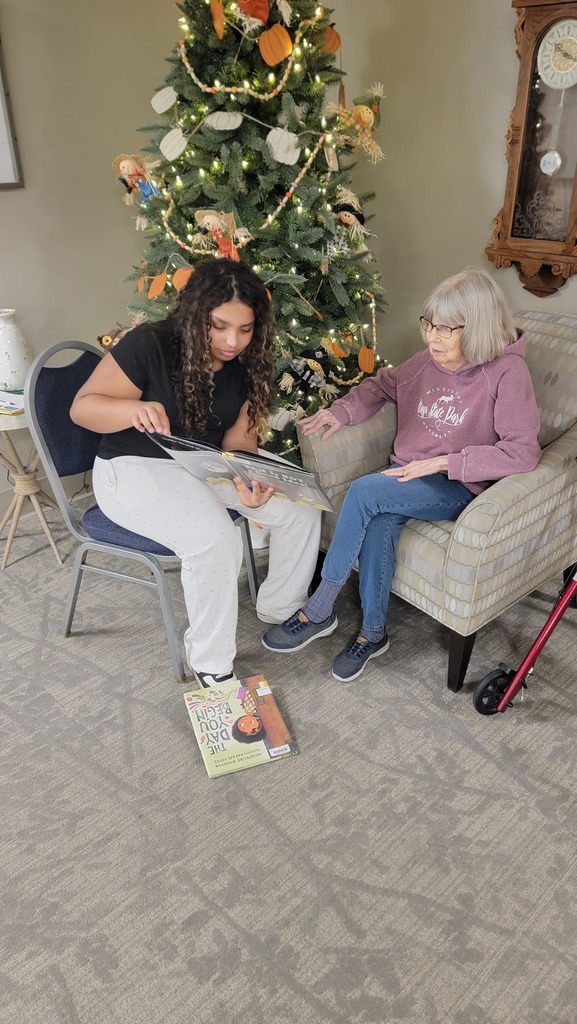 A student reading to a resident at Parker Oaks