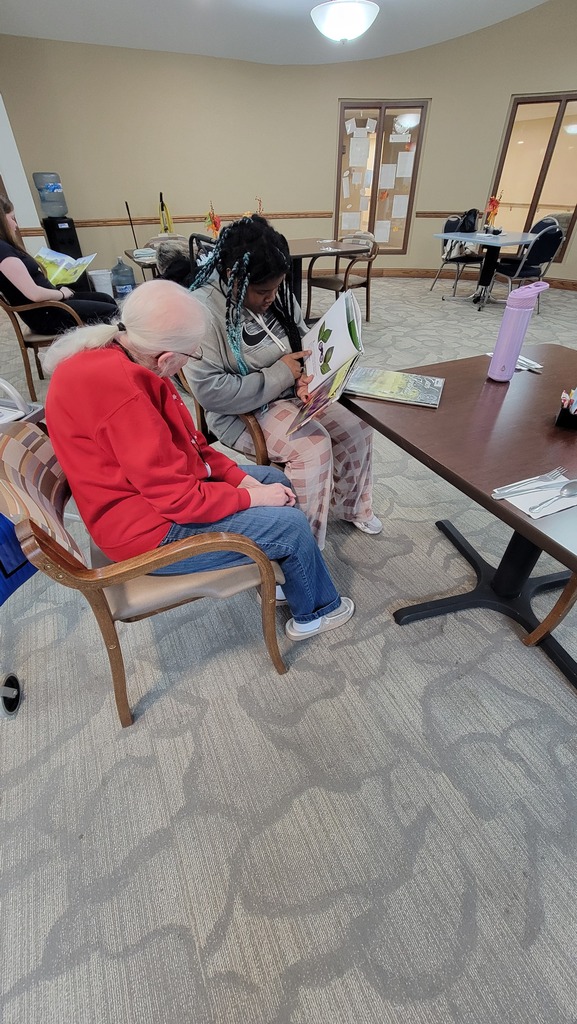 A student reading to a resident at Parker Oaks
