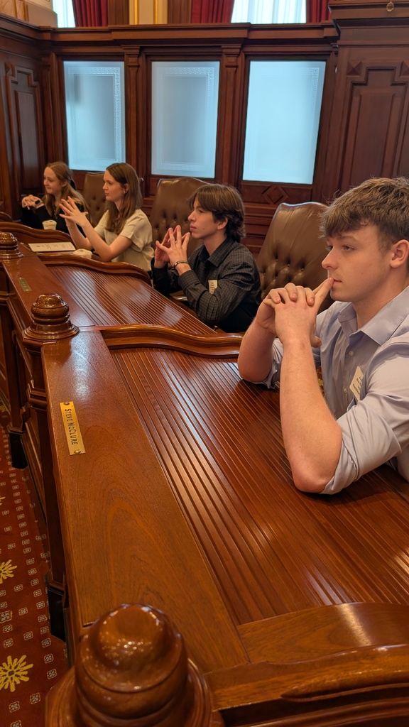 Haylee Dean, Kelly Weiss, Thomas Vanderspool, and AJ Bernard deep in thought in the Illinois Senate seats.