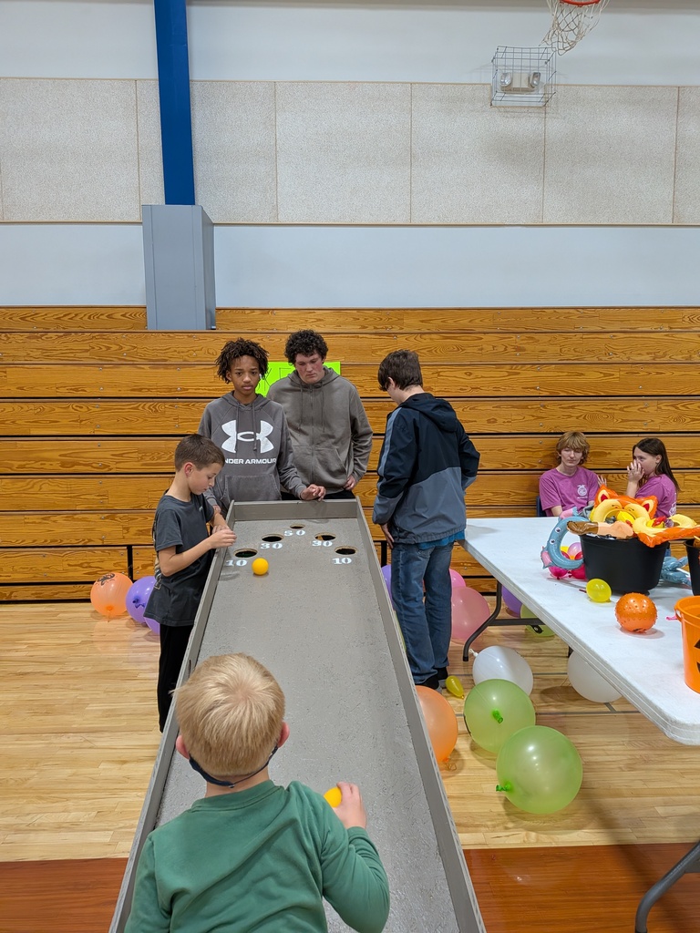 Shamar, Liam and Colton assist some early visitors in playing skee ball 