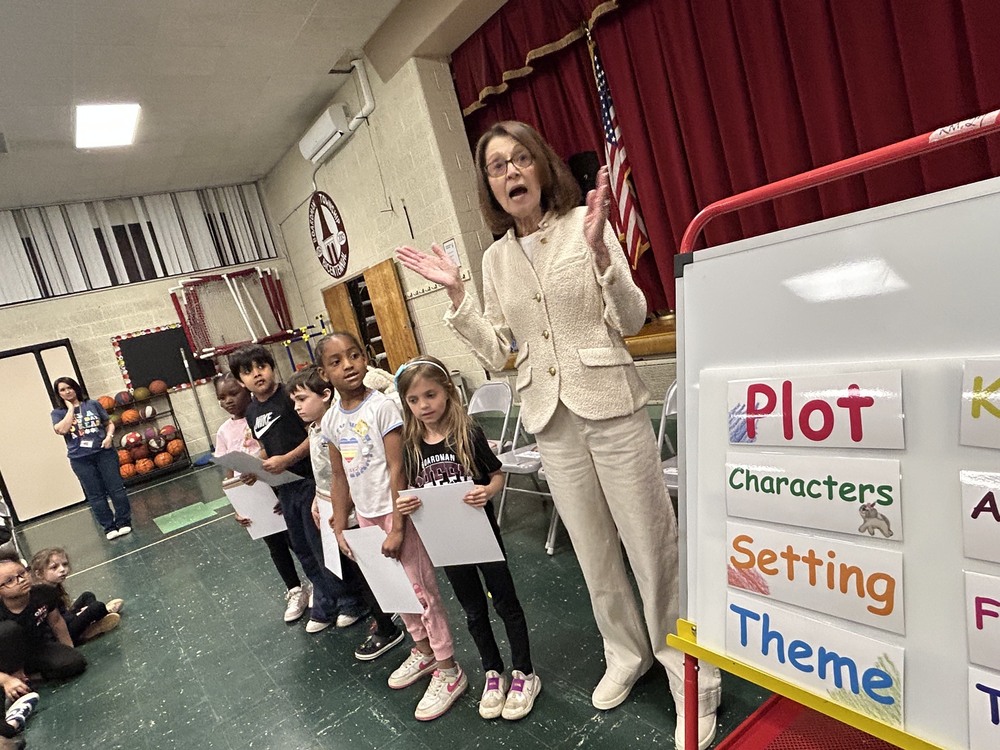 Author Linda Krieger standing with robinwood students and a board that says plot, characters, setting