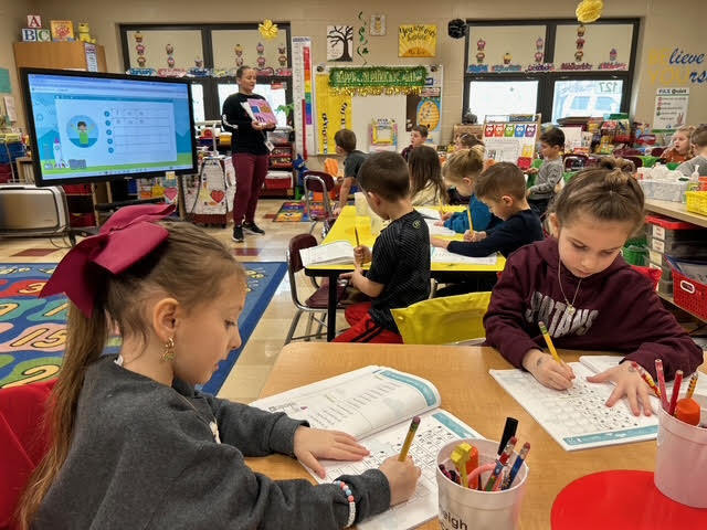 Kindergarten students writing in workbooks