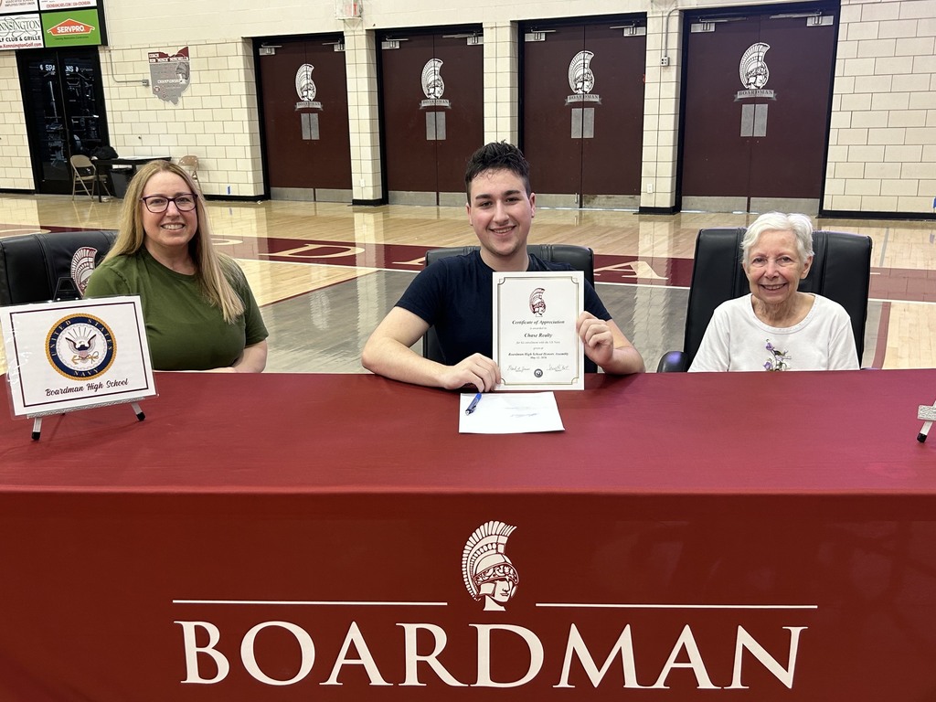 Chase Realty  holding up certificate with relatives sitting with him at signing table
