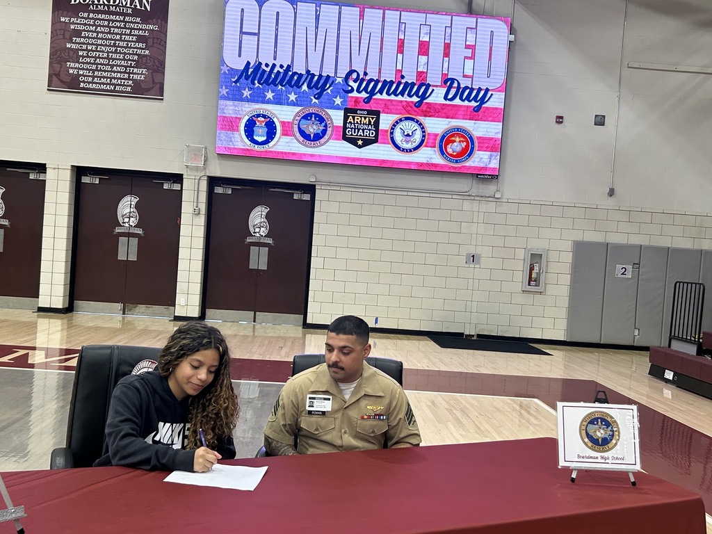 Carmen Cortez signing at Military signing table with recruiter sitting next to her