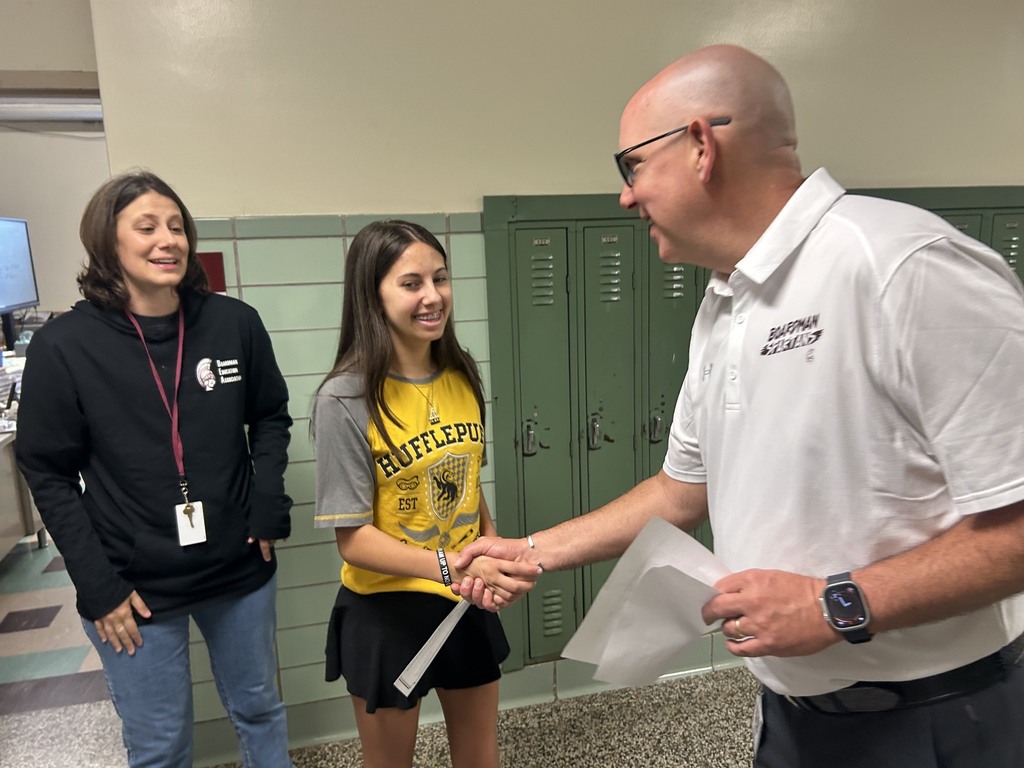 board member mr. murray shaking hands with cecilia and her science teacher