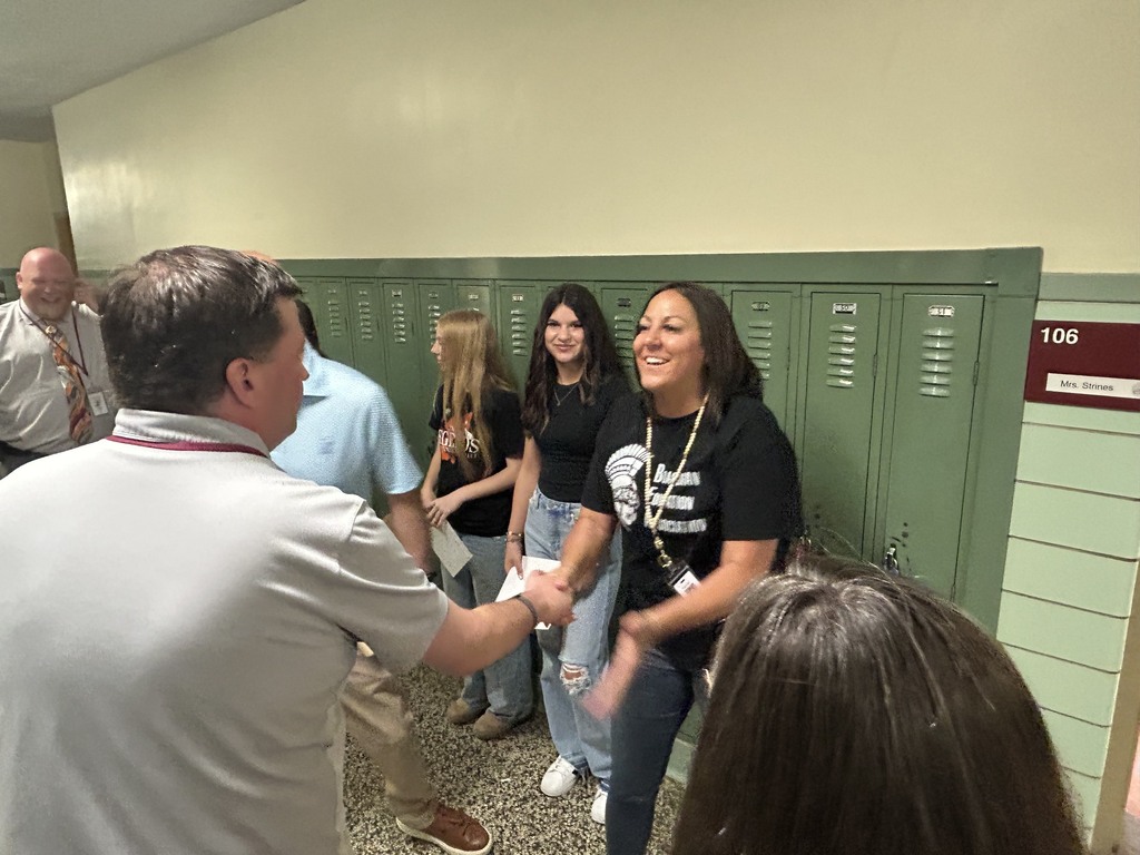 board member mr. landers shaking hands with mrs. strines two students who scored perfect in ELA