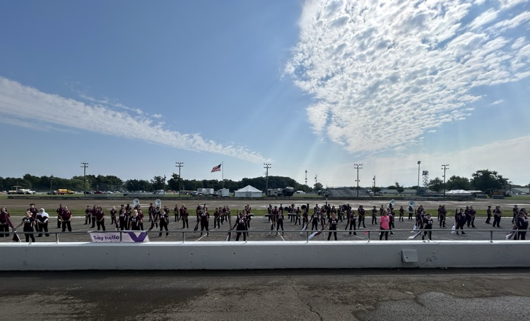 full photo of entire band on the track performing at the grandstand
