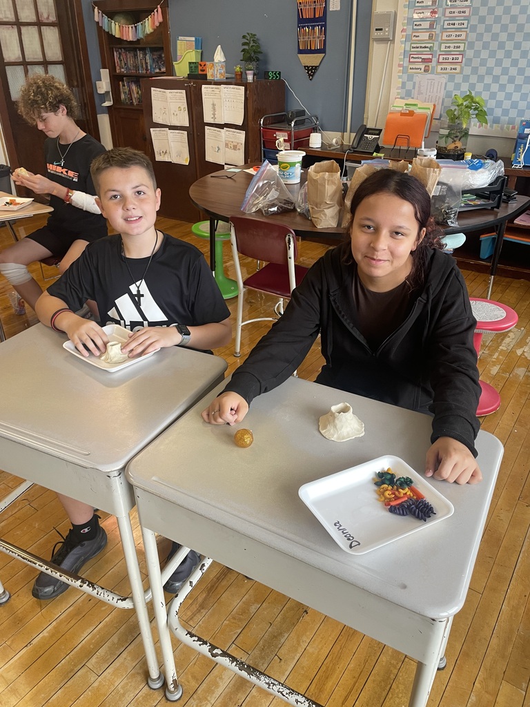 two students at their desk finishing their volcano projects