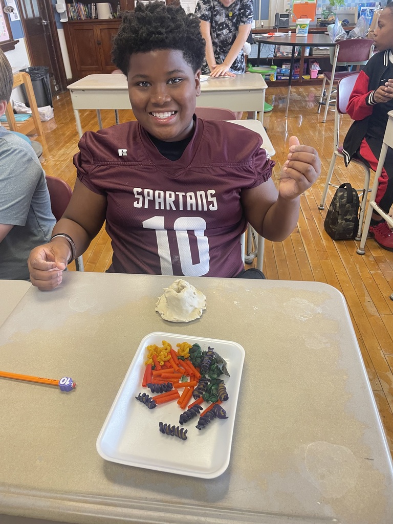 boy with his clay volcano and colored pasta to decorate