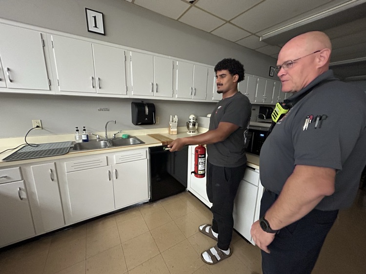 student practicing using fire extinguisher in student kitchen