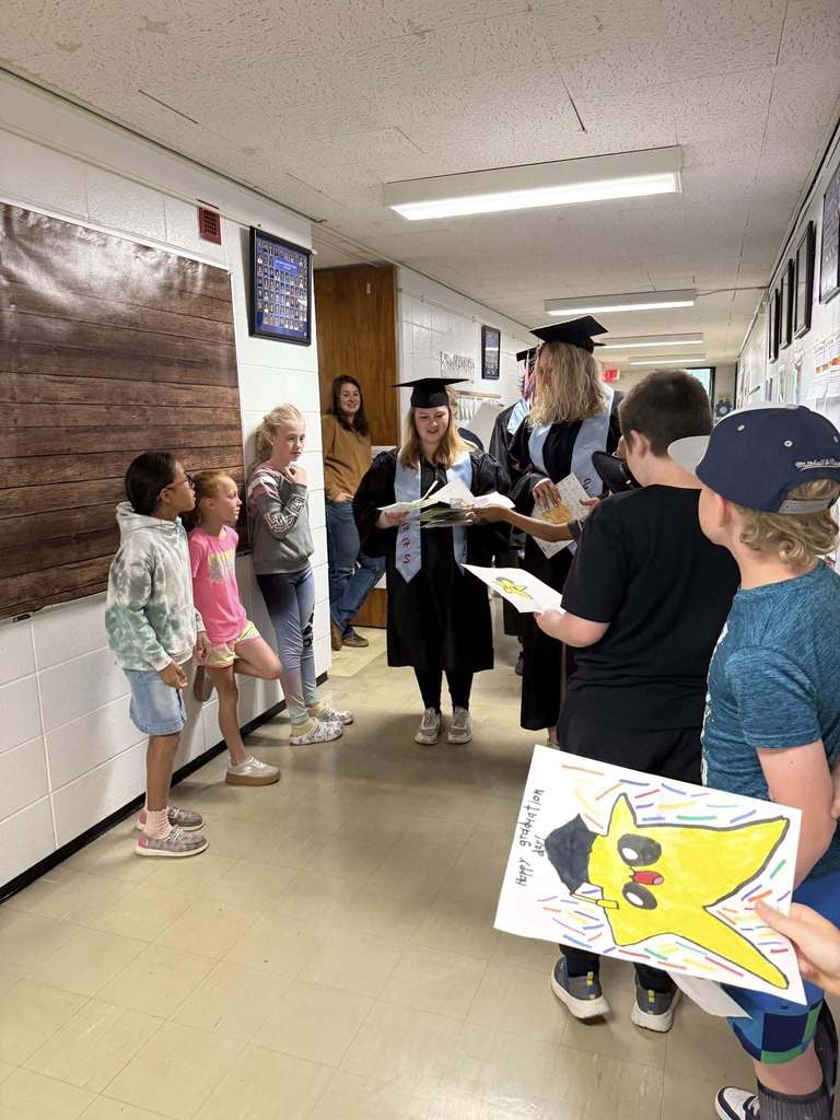 Elementary students handing drawings to high school graduates