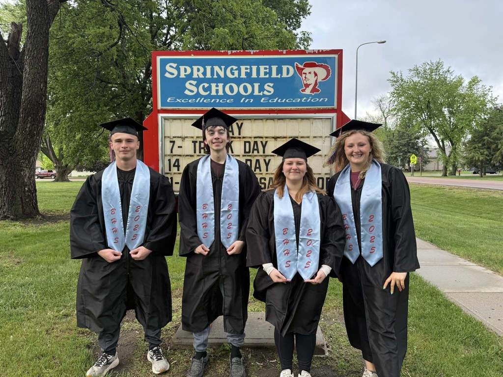 High School graduates in front of the school's sign